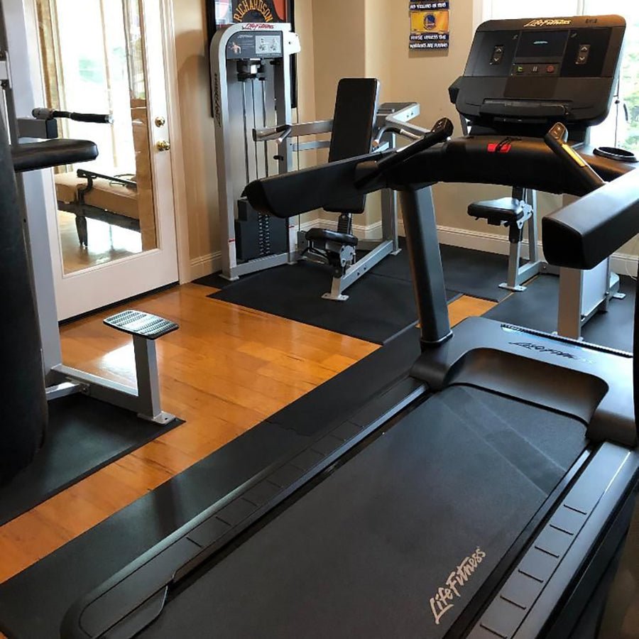 Hammer Strength urethane dumbbells and fixed barbells arranged in a commercial home gym setting